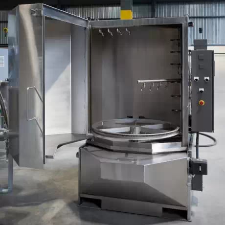 Interior view of the TYPHOON®-PCE parts washer, showcasing the cabinet-mounted turntable and C-shaped spray manifold for comprehensive cleaning.